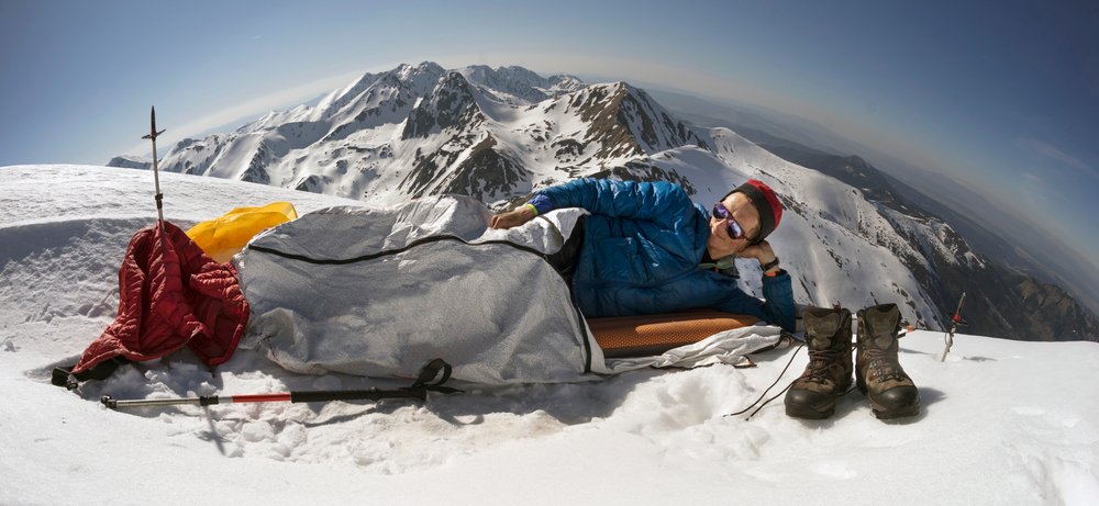 muž ležici ve spacáku v horách